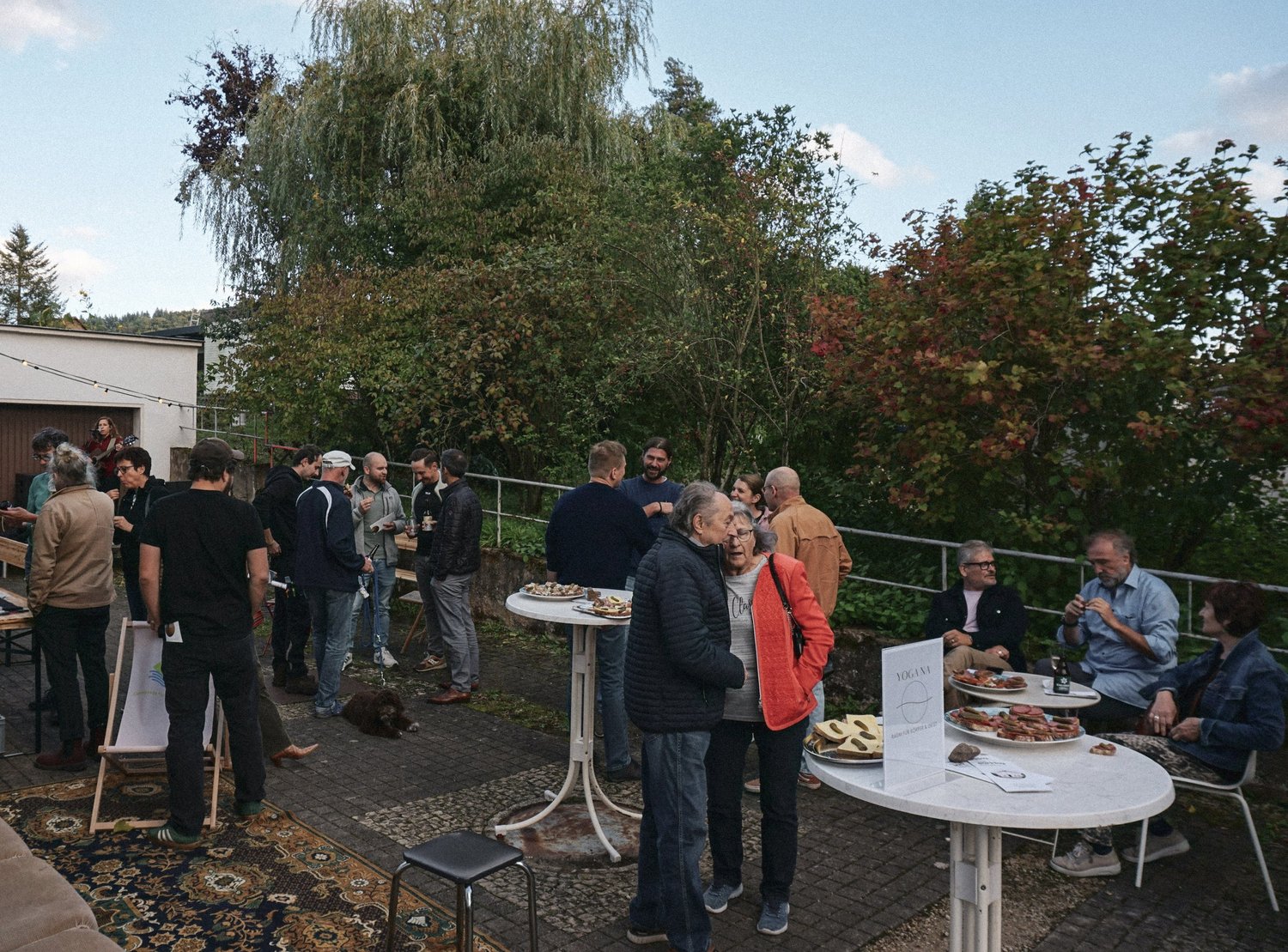 Gäste stehen und sitzen an Stehtischen im Hof des Coworking-Space.