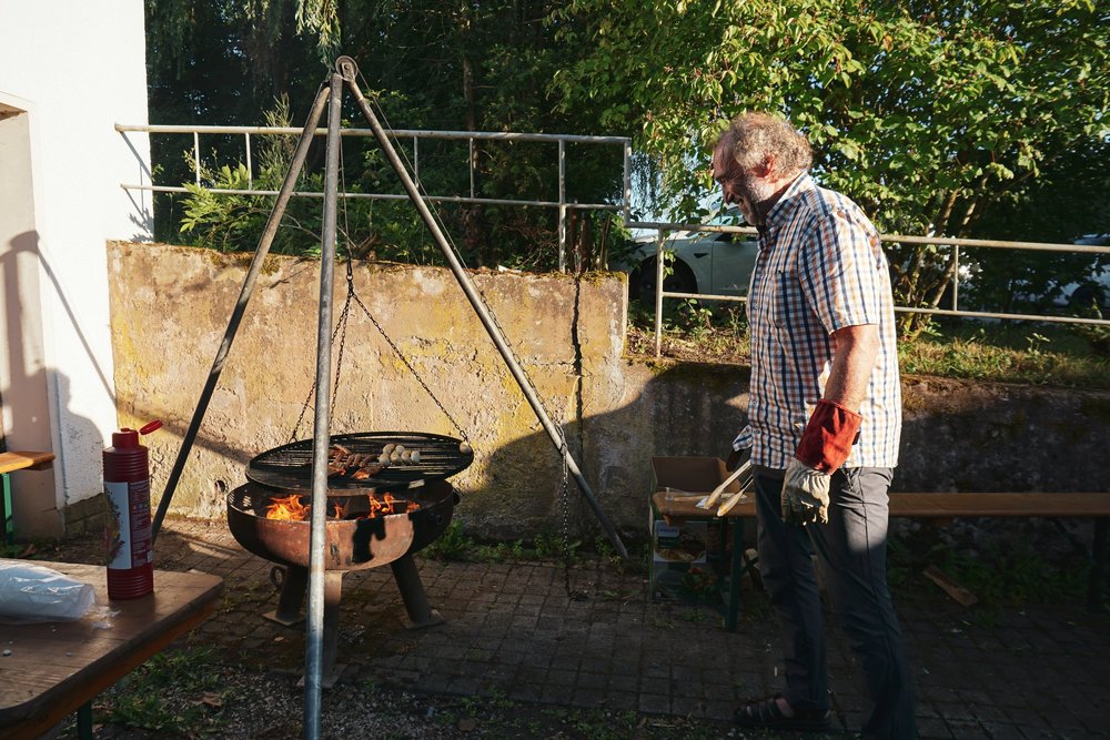 Un homme en chemise à carreaux s’occupe du grill suspendu.