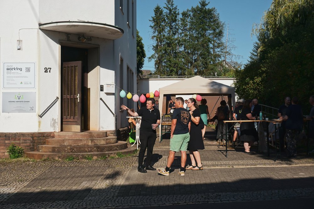 Invités devant l’entrée du bureau au numéro 27, guirlandes et barnum dans la cour.
