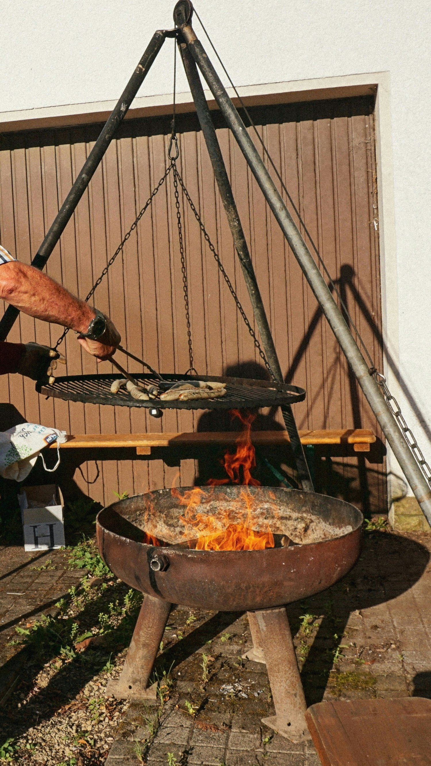 Grill suspendu au-dessus d’un feu ouvert dans la cour.