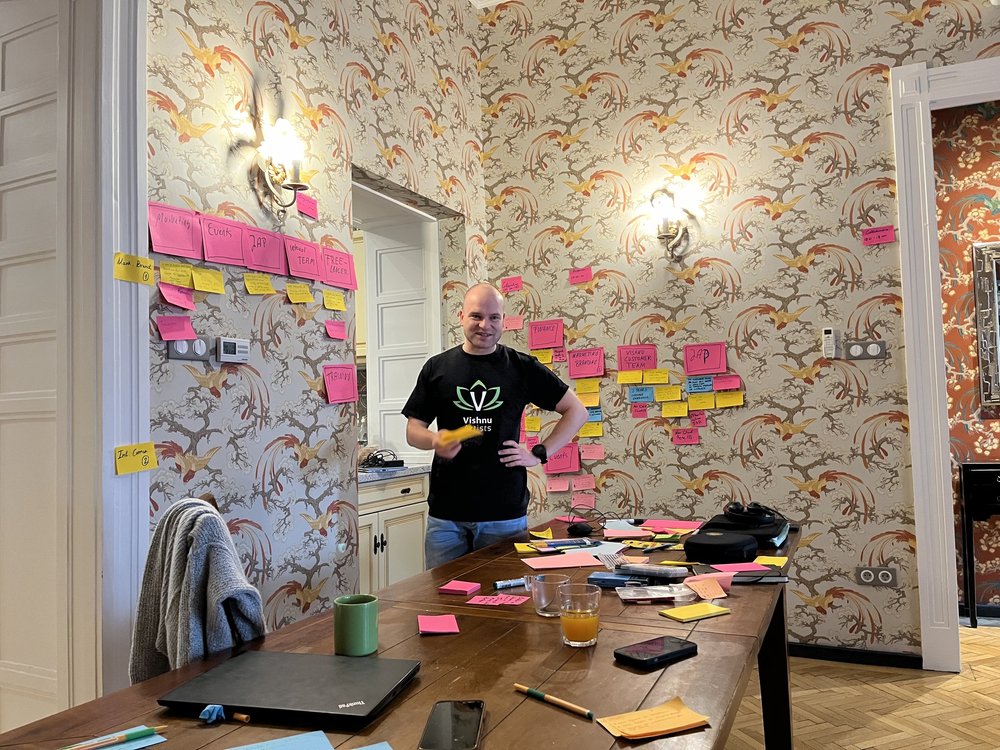 Kollege im Vishnu-Artists-Shirt vor einer Wand voller Haftnotizen.