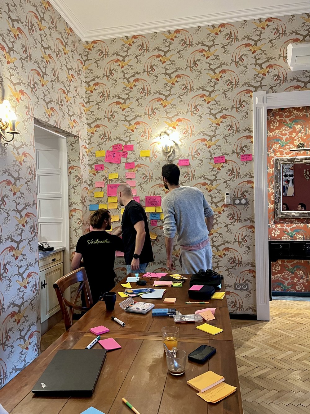 Drei Kollegen arbeiten an der Haftnotizen-Wand.